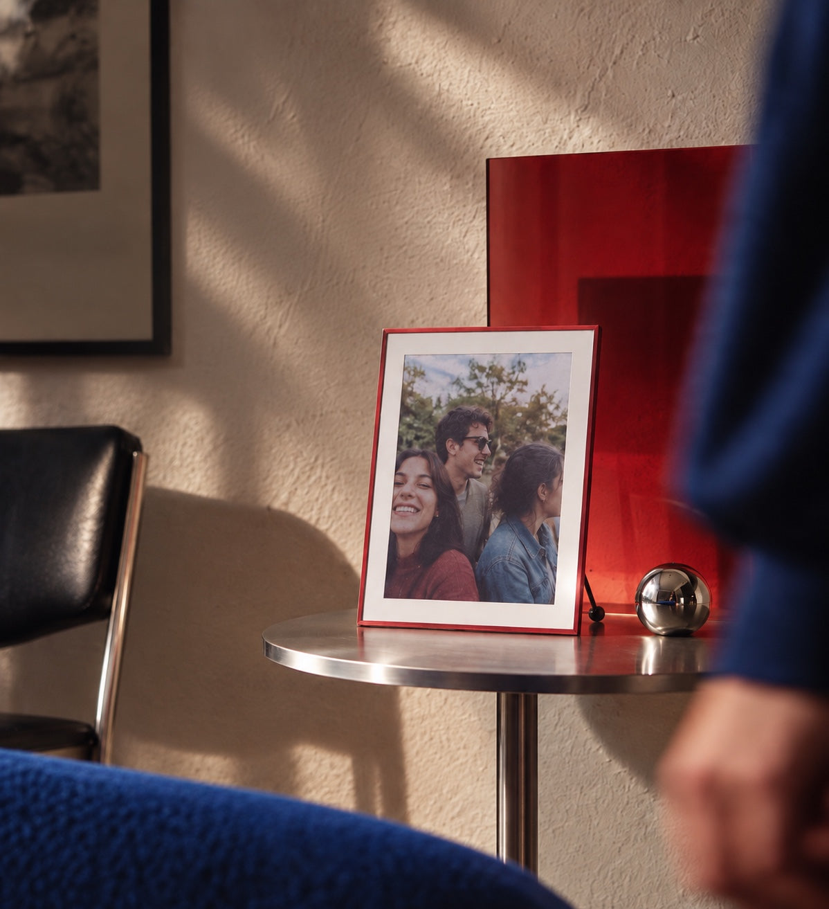 A red BLOOMIN8 frame displaying a personal photo in a warm interior